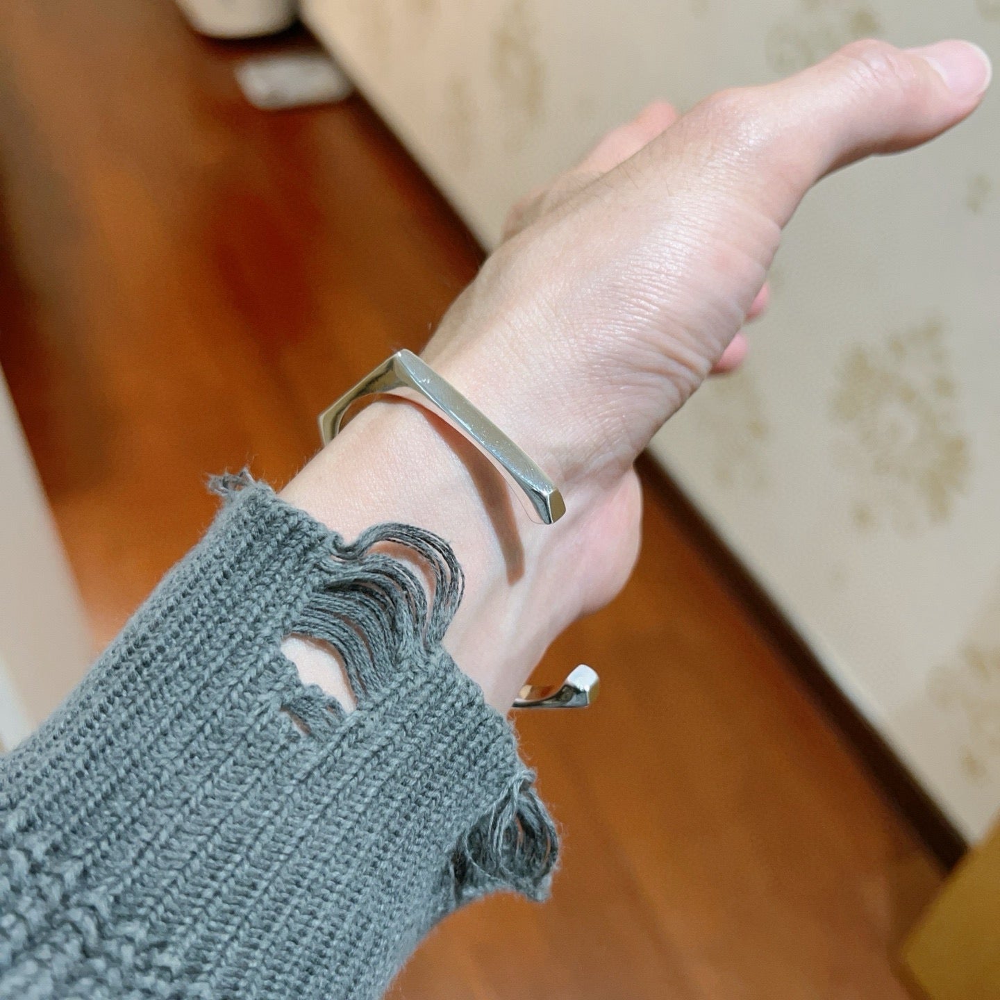 Gucci silver bangle worn on wrist, brushed metal cuff with engraving