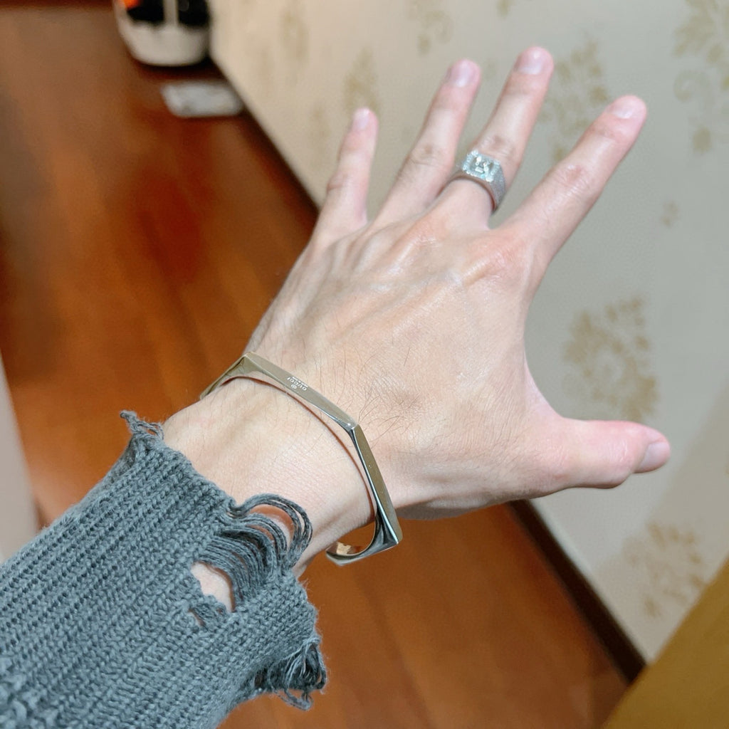 Gucci silver bangle on open hand, cuff with engraved logo