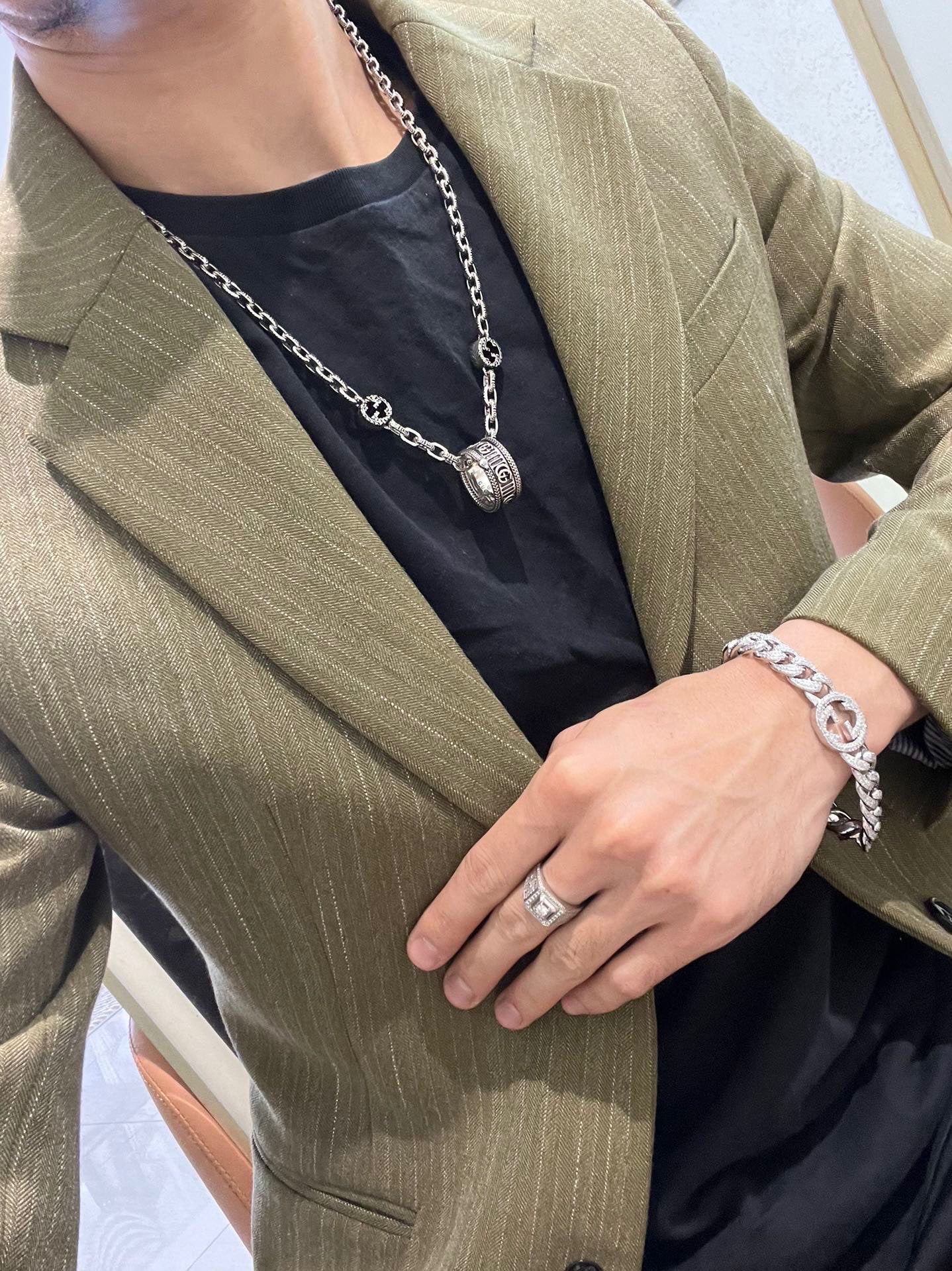 Silver-tone chain necklace with round logo charm pendant on dark top