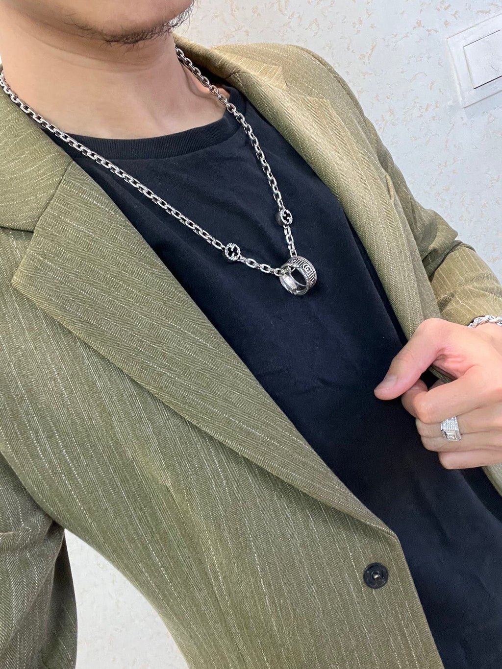 Silver-tone chain necklace with small oval logo pendant near collar