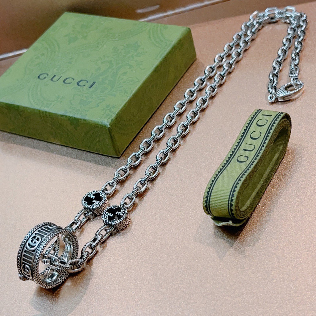 Silver-tone chain necklace with round black enamel medallion and large oval logo clasp