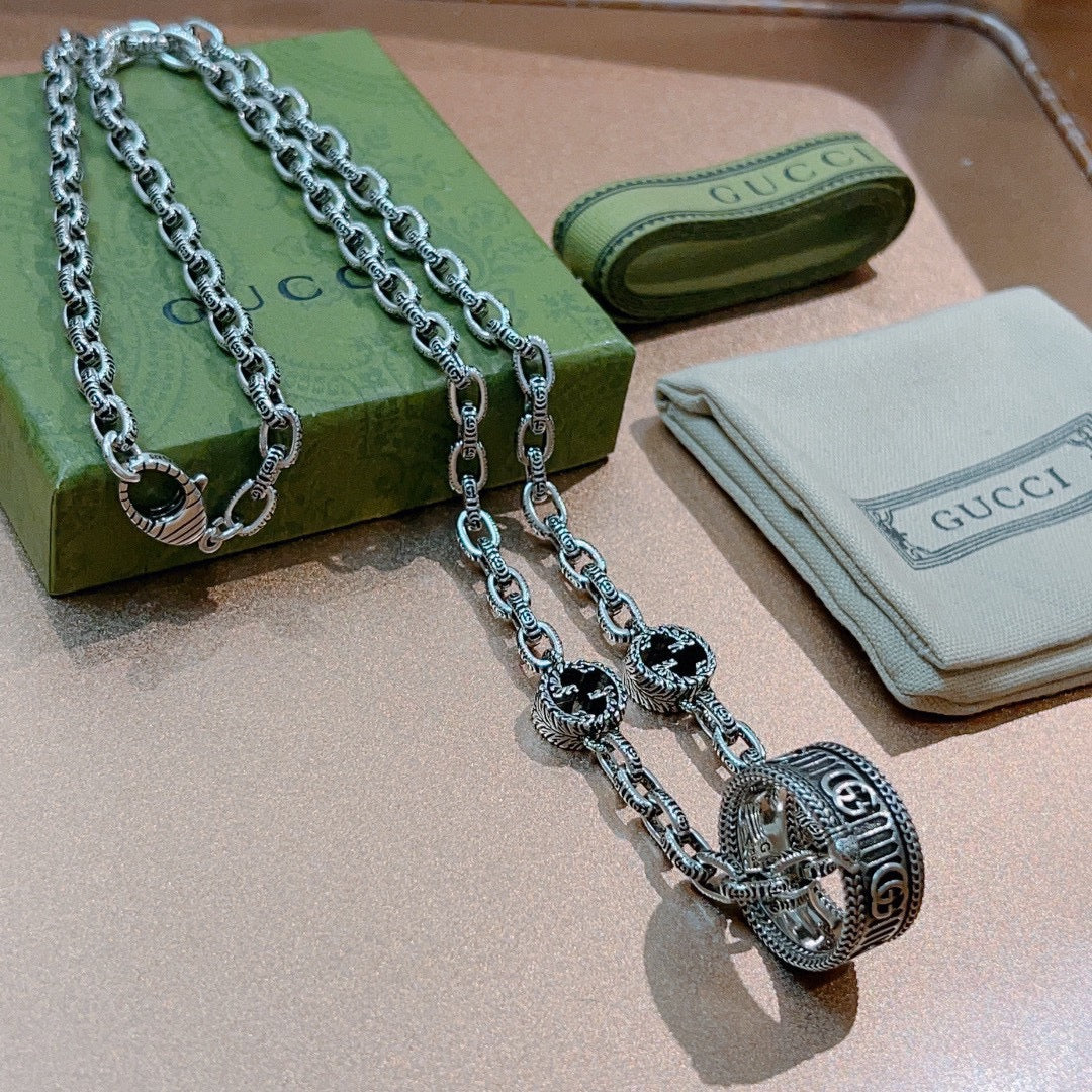 Silver-tone chain necklace with two oval black enamel pendants and large round logo clasp