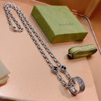 Silver-tone chain necklace with round black enamel medallion and engraved details