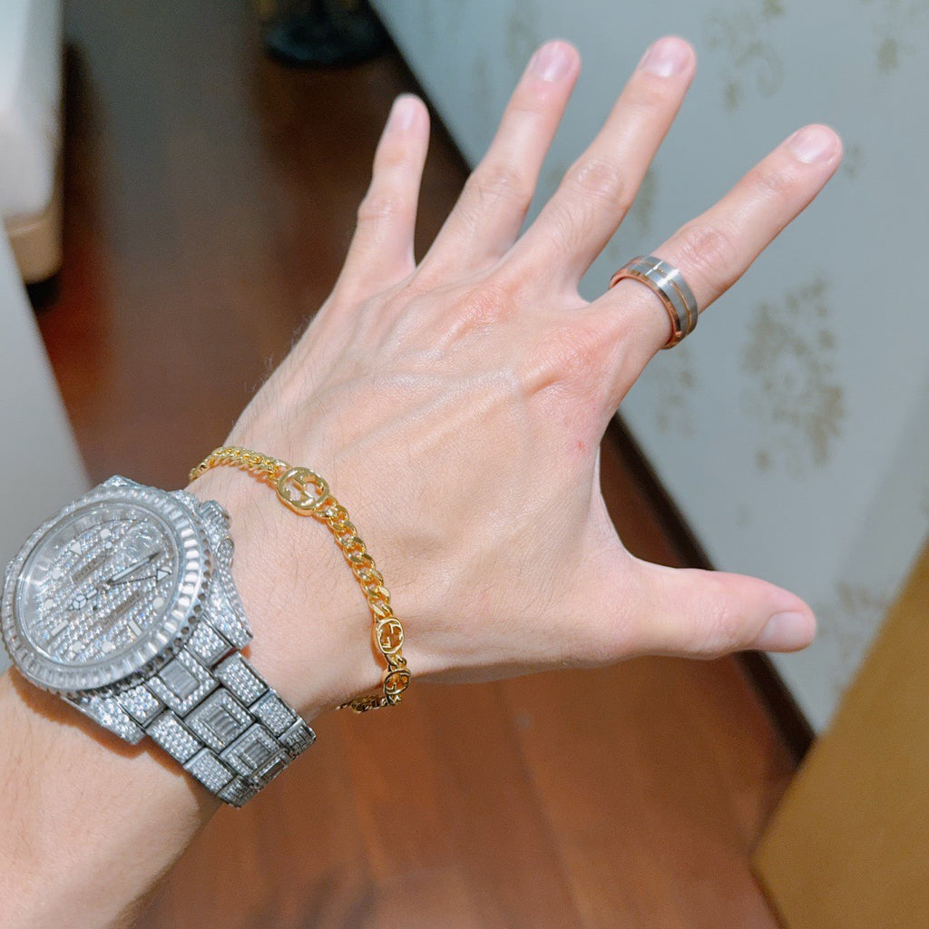 Gold chain bracelet with round links on wrist.