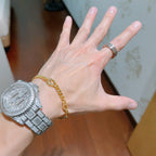 Gold chain bracelet with round links on wrist.