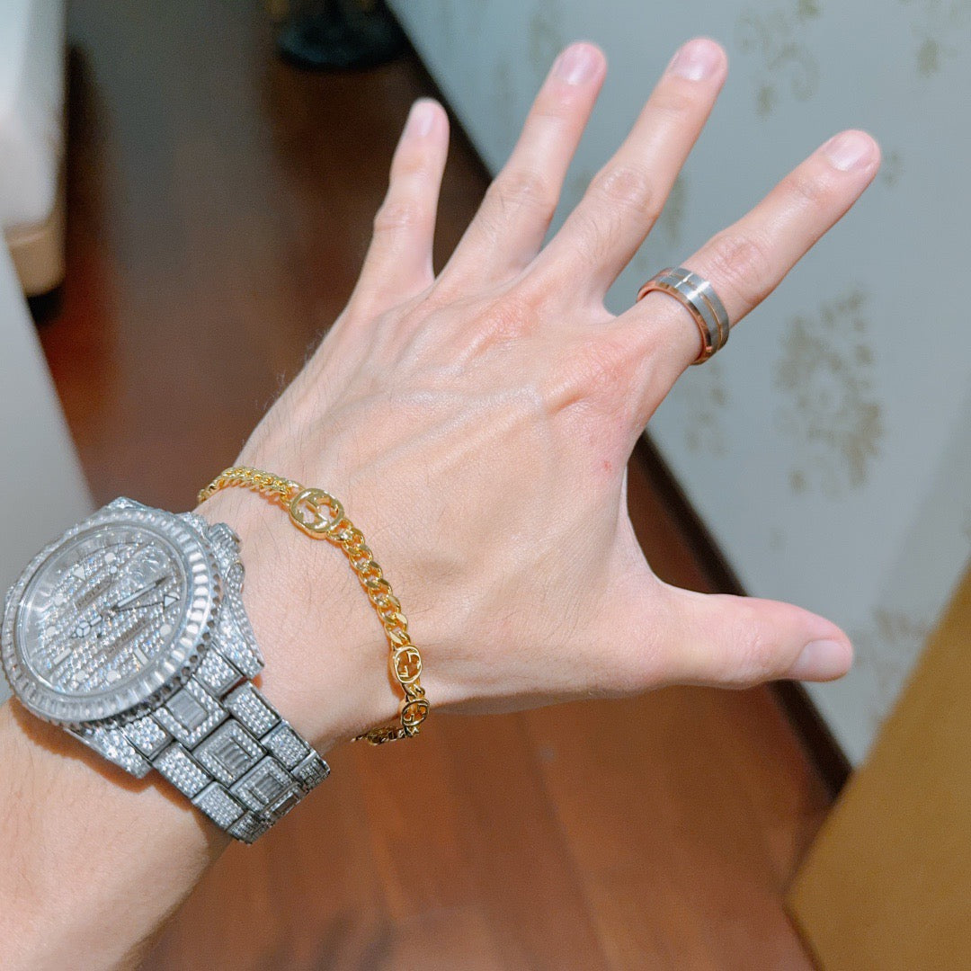Gold chain bracelet with round links on wrist.