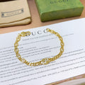 Gold chain bracelet with round links and clasp, laid on a paper insert.