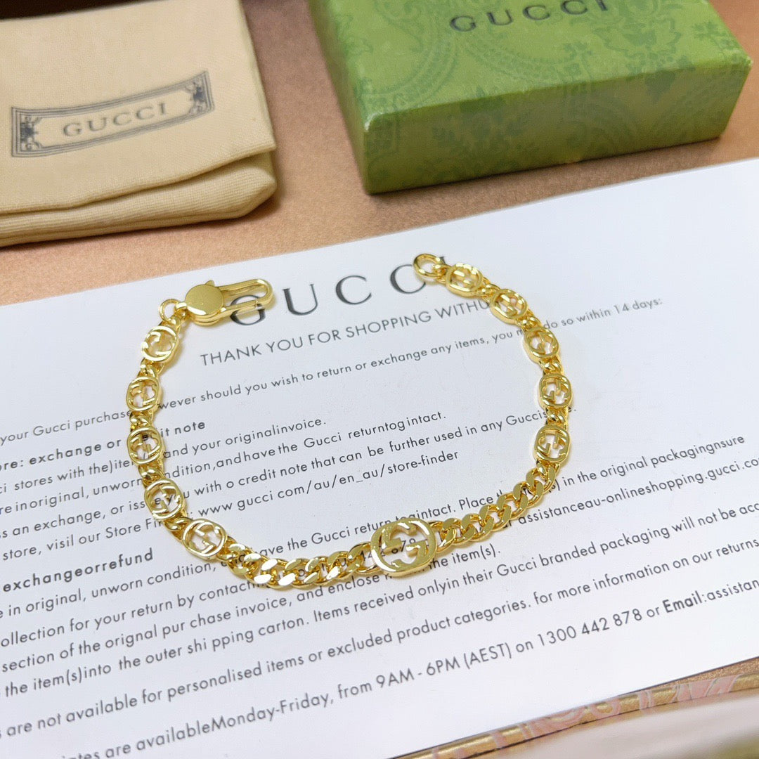 Gold chain bracelet with round links and clasp, laid on a paper insert.