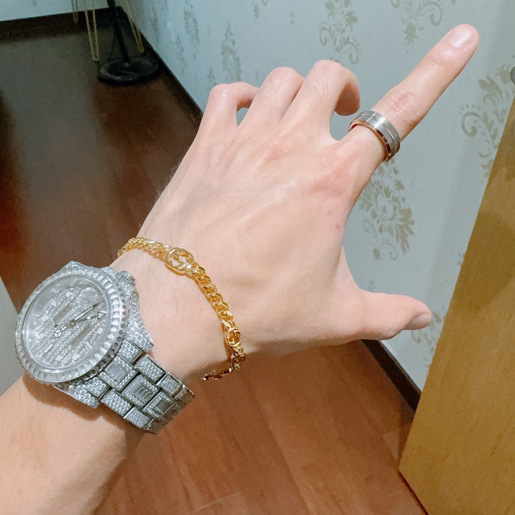 Gold chain bracelet with round links on hand, clasp near wrist.
