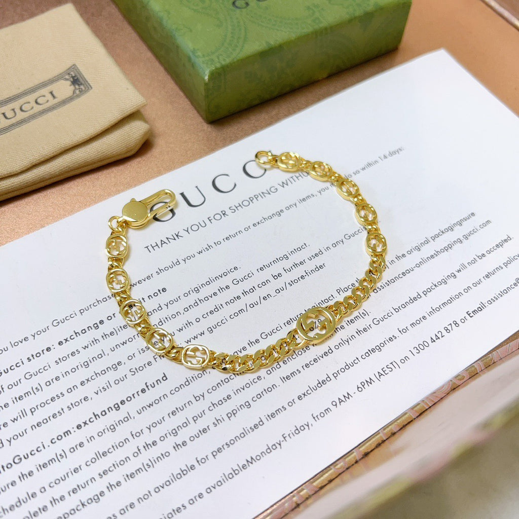 Gold chain bracelet with round links and clasp, resting on paper.