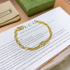 Gold chain bracelet with round links and clasp, resting on paper.