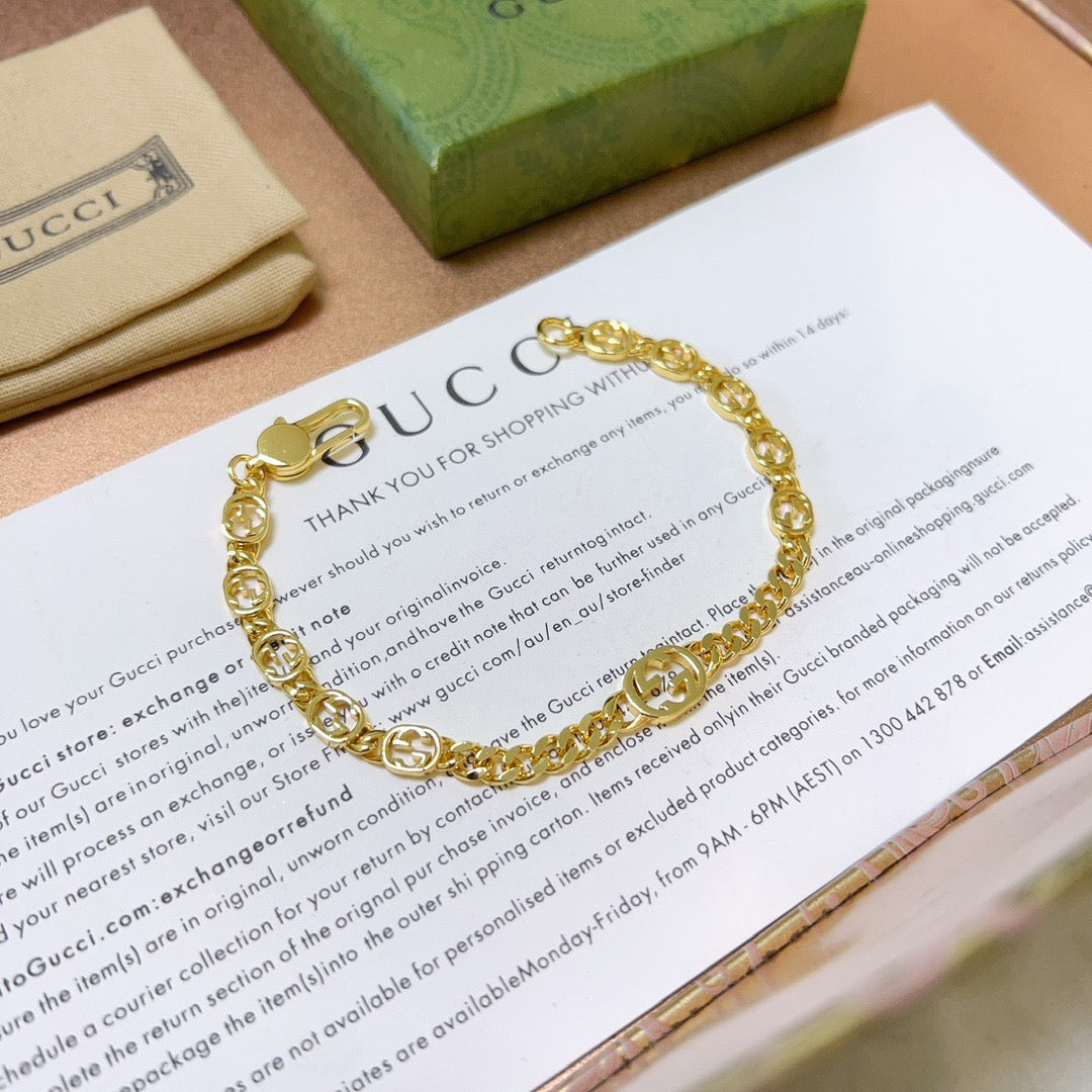 Gold chain bracelet with round links and clasp, resting on paper.