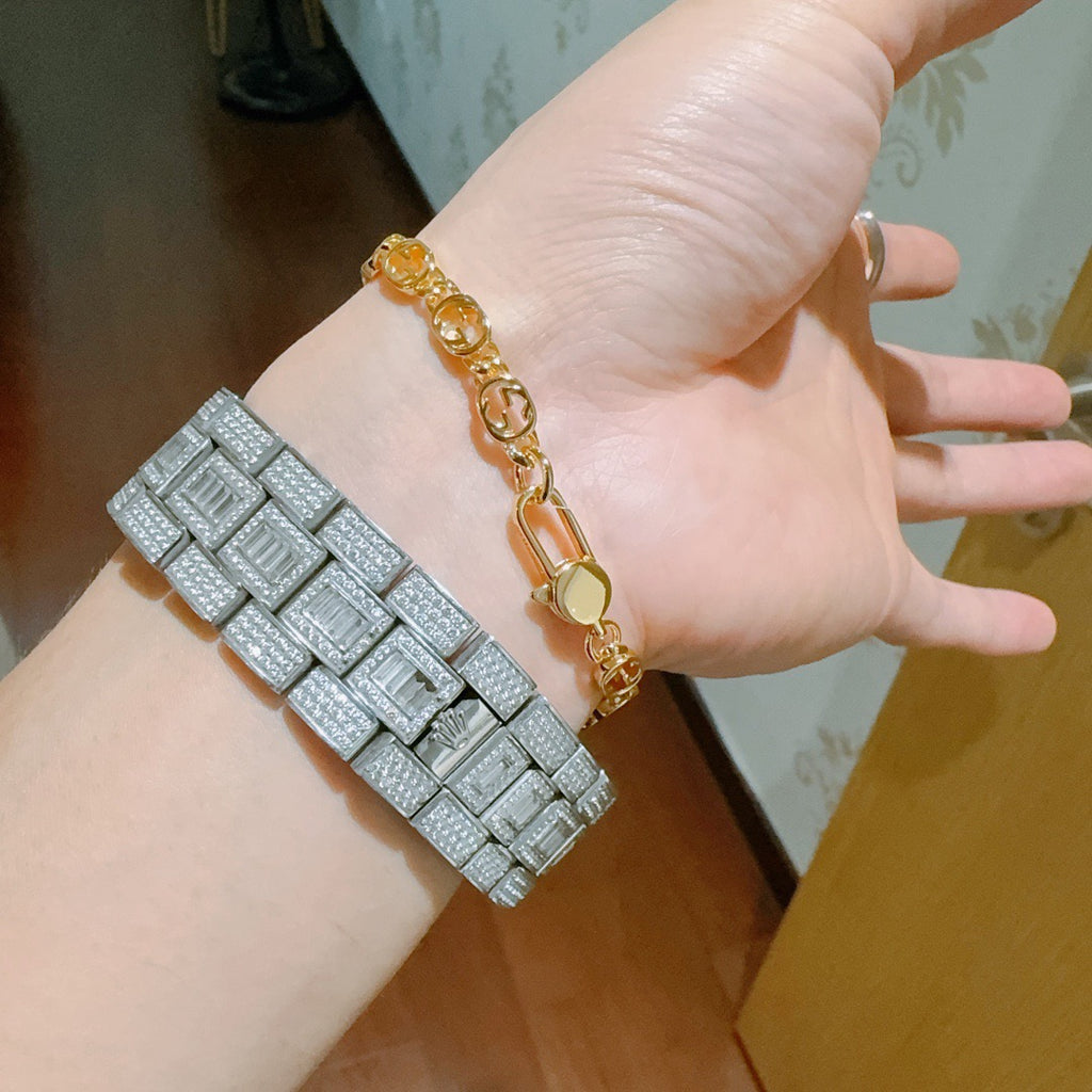 Gold chain bracelet close-up with oval links and clasp on hand.