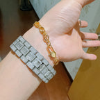 Gold chain bracelet close-up with oval links and clasp on hand.