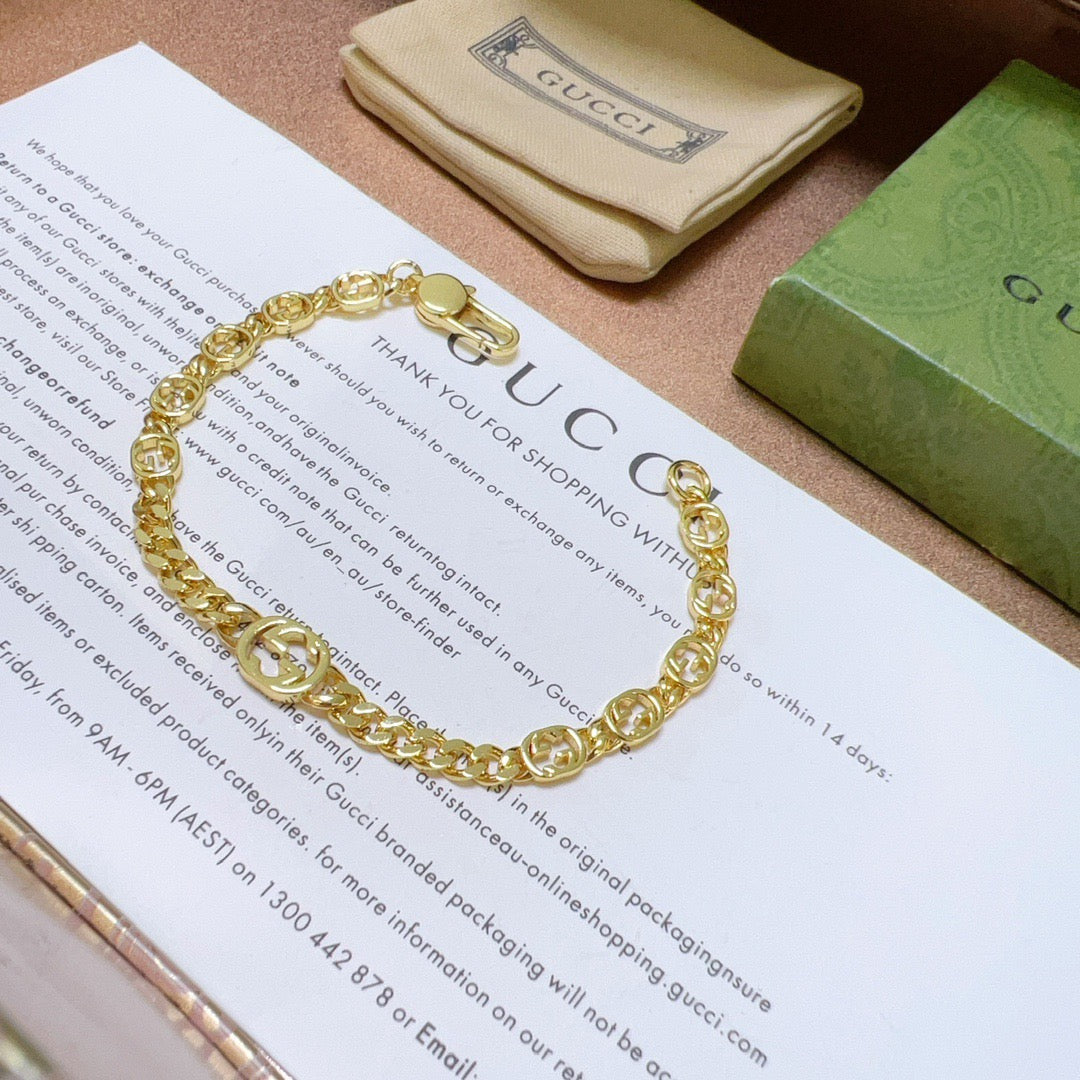 Gold chain bracelet with round links and clasp, on a card and pouch.