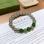 Silver charm bracelet with green beads, viewed from the front