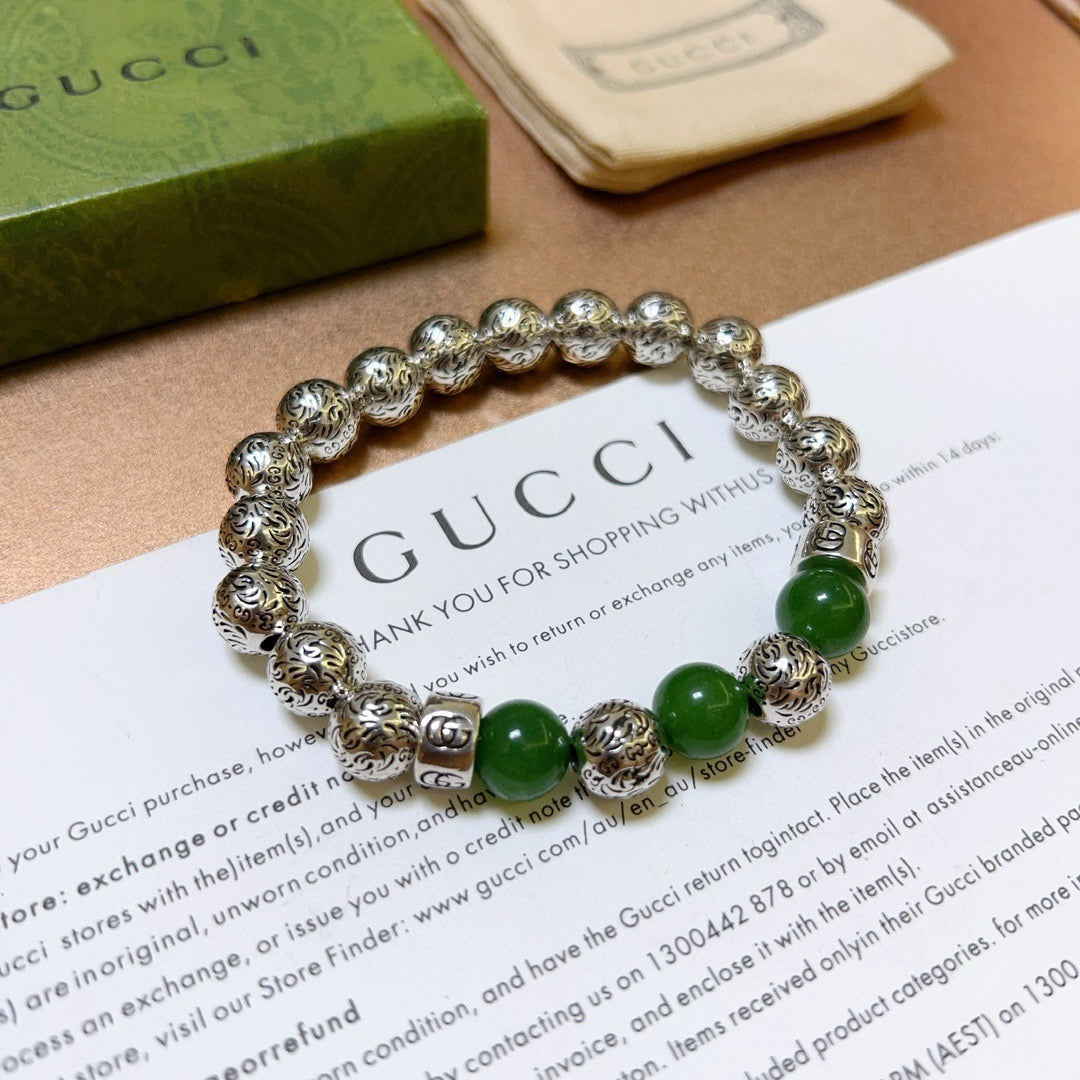 Silver charm bracelet with green beads, viewed from the front
