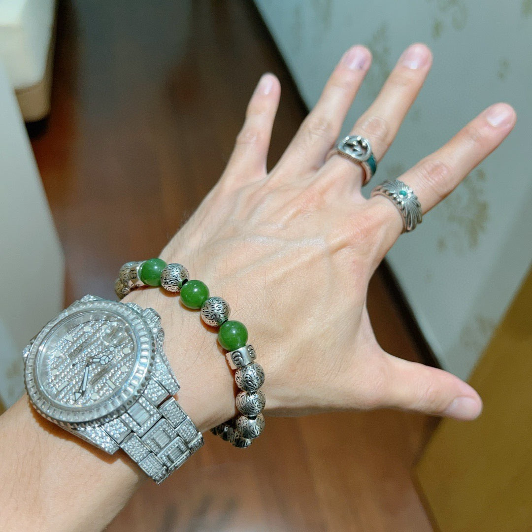 Green beaded silver charm bracelet on an open hand