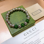 Silver bead bracelet with green bead accents and engraved round charms