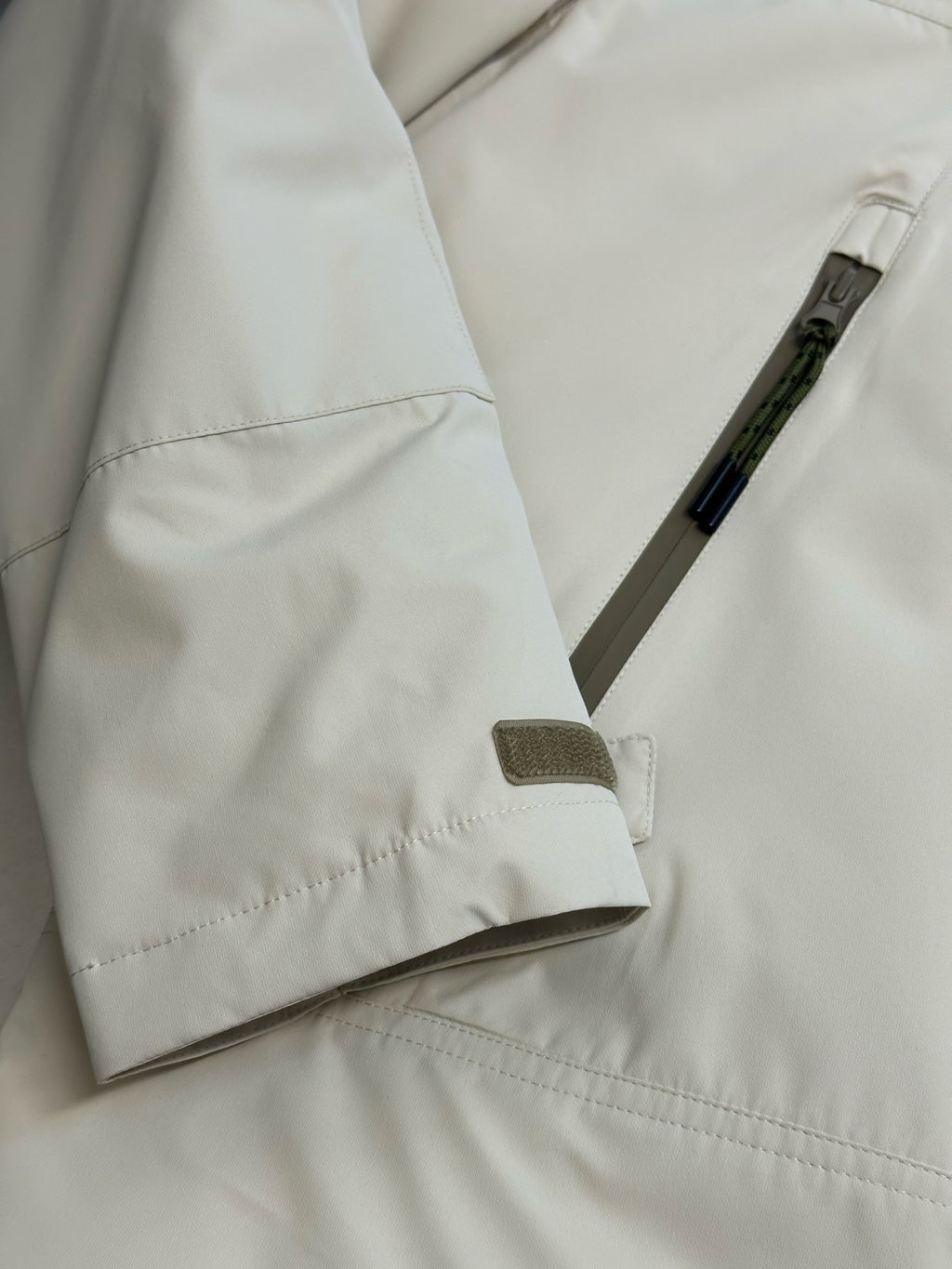 Light beige hooded jacket close-up with drawcord tab and side snap pocket