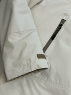 Light beige hooded jacket close-up with drawcord tab and side snap pocket