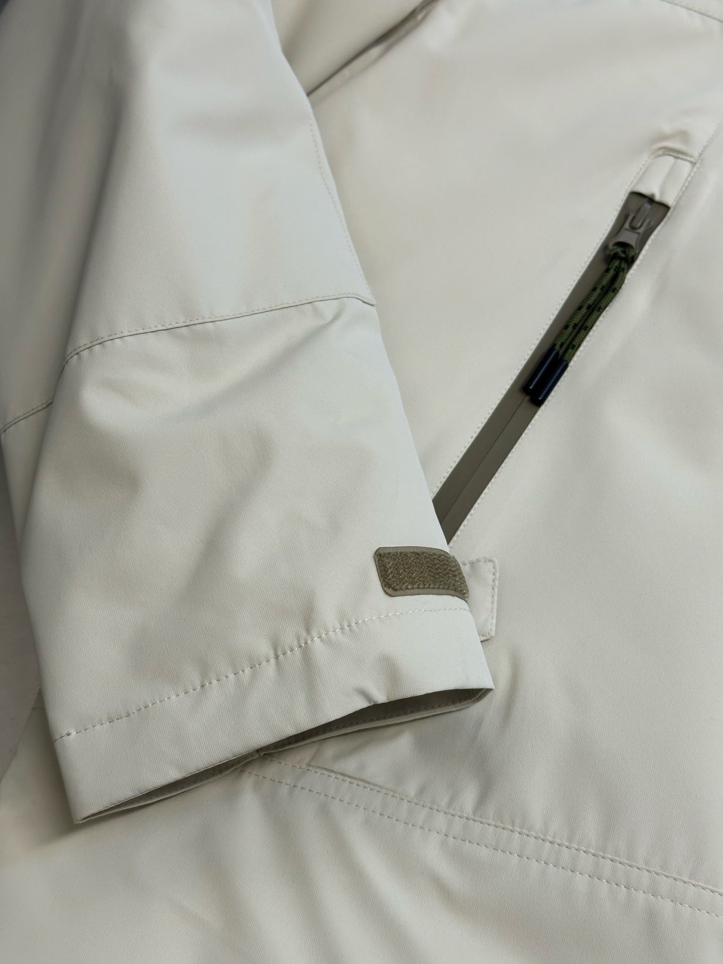 Light beige hooded jacket close-up with drawcord tab and side snap pocket