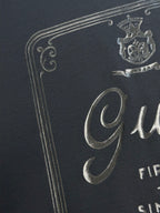 Dark navy T-shirt close-up of metallic crest and Gucci logo print