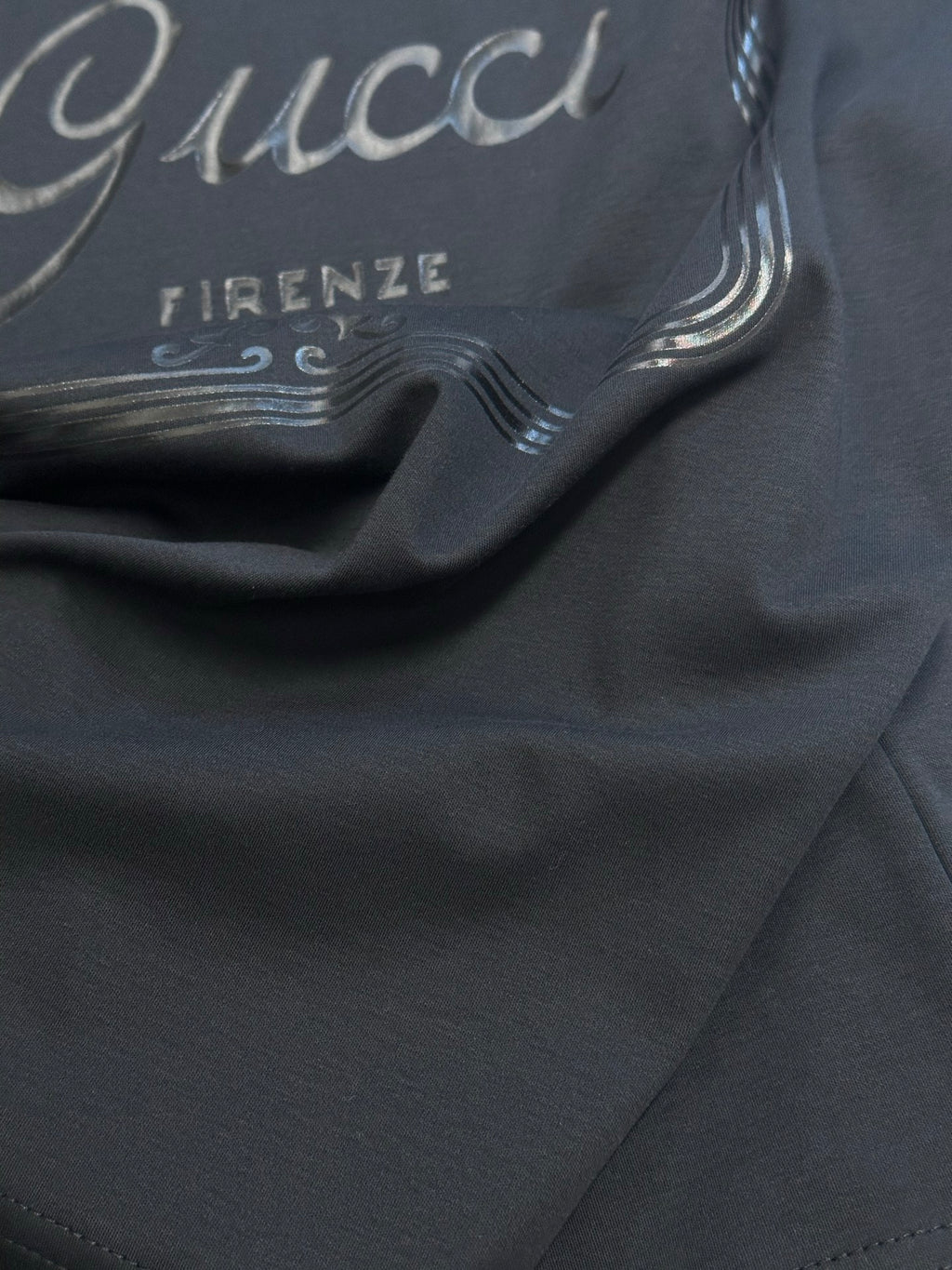 Dark navy T-shirt fabric close-up with partial Gucci and Firenze print