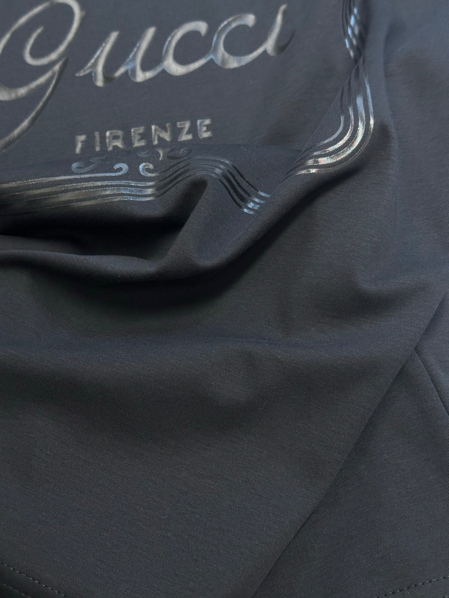 Dark navy T-shirt fabric close-up with partial Gucci and Firenze print