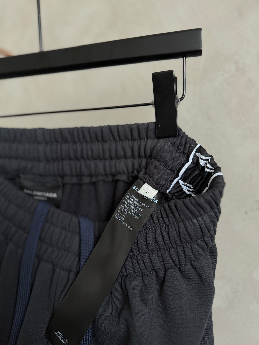 Dark navy pants on hanger, elastic waistband with drawcord and attached tag.