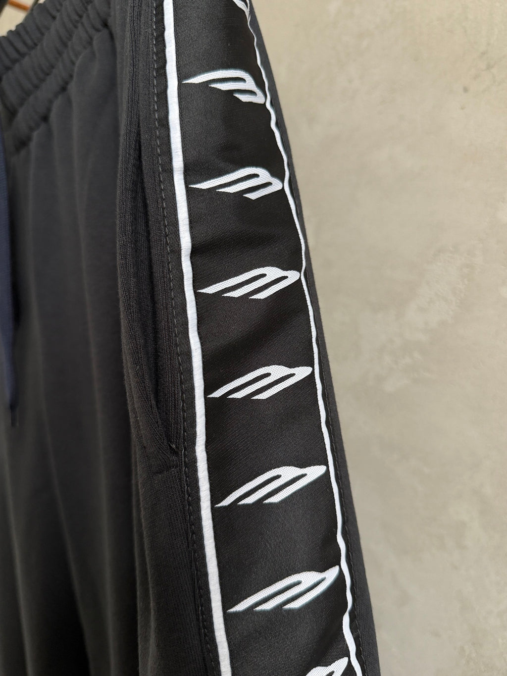 Dark navy pants with white repeating logo stripe and black stitched side seam.