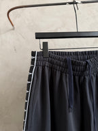 Dark navy drawstring pants with elastic waist and side logo stripe.