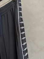 Dark navy pants with white logo stripe on the side and pleated front detail.