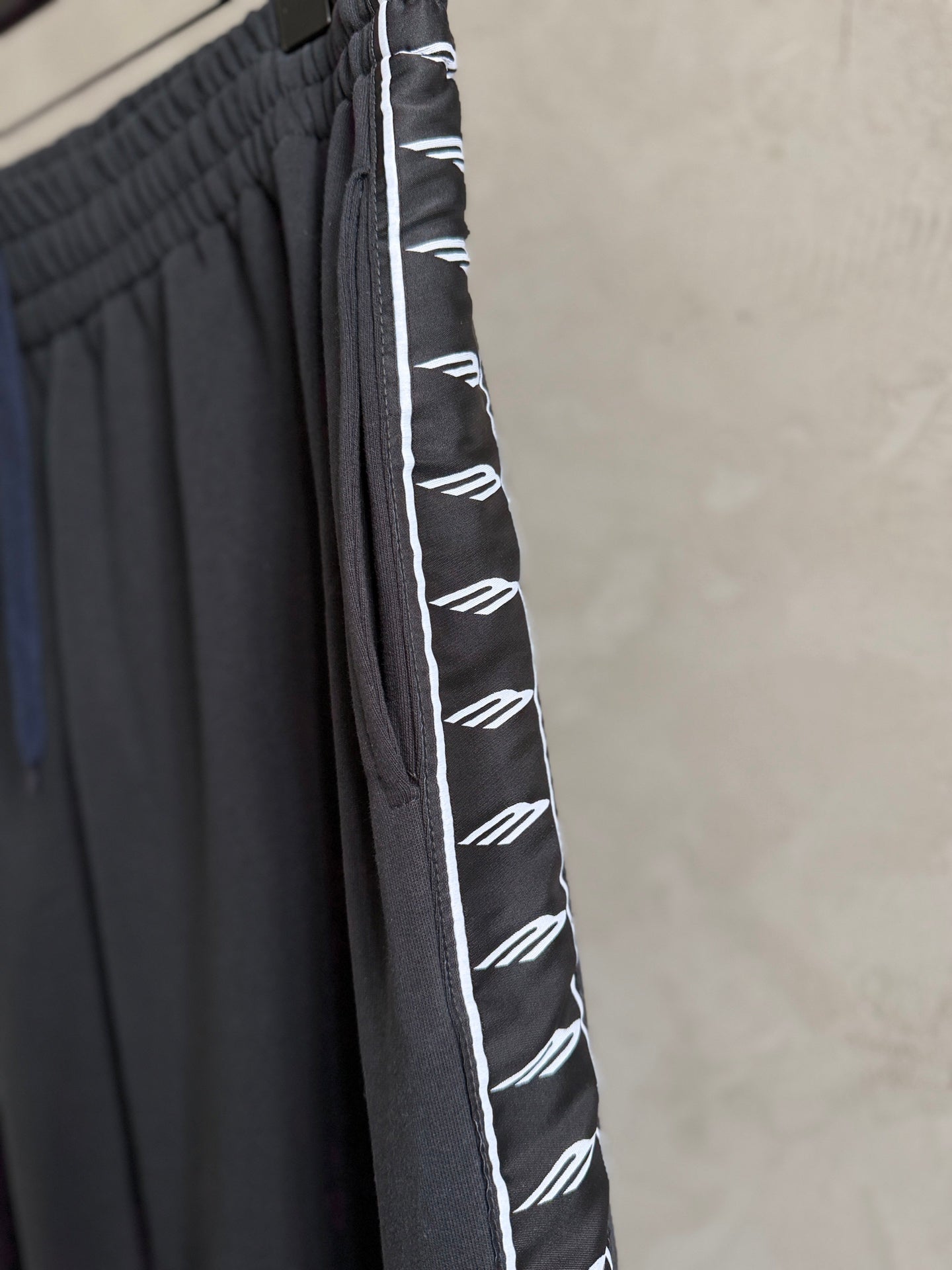 Dark navy pants with white logo stripe on the side and pleated front detail.