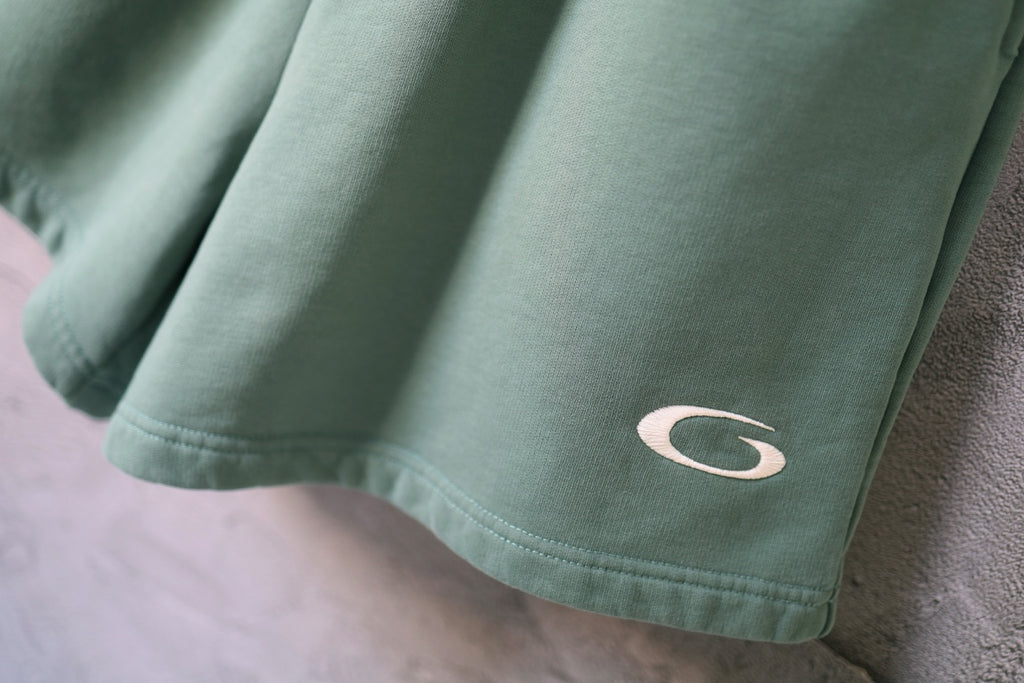 Teal shorts hem with small curved logo embroidery