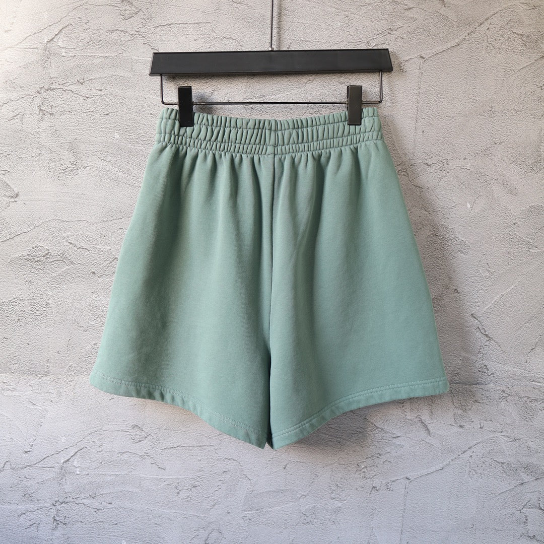 Teal shorts with elastic waistband and small curved logo on the right hem