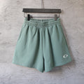 Teal drawstring shorts with elastic waistband and small curved logo patch