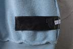 Light blue hoodie sleeve with black brand fabric label at cuff