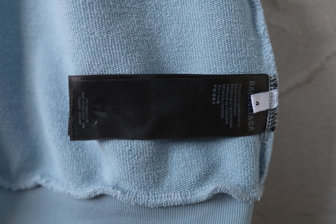 Light blue hoodie sleeve with black brand fabric label at cuff