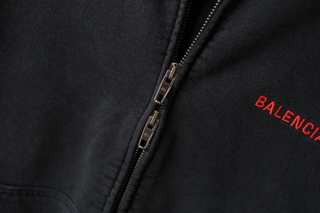 Black zip hoodie with metal zipper; red BALENCIAGA logo near the zipper edge.