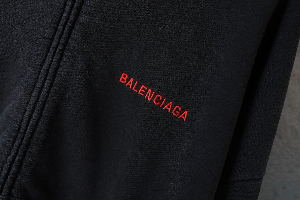 Black hoodie with small red BALENCIAGA logo print on chest area.