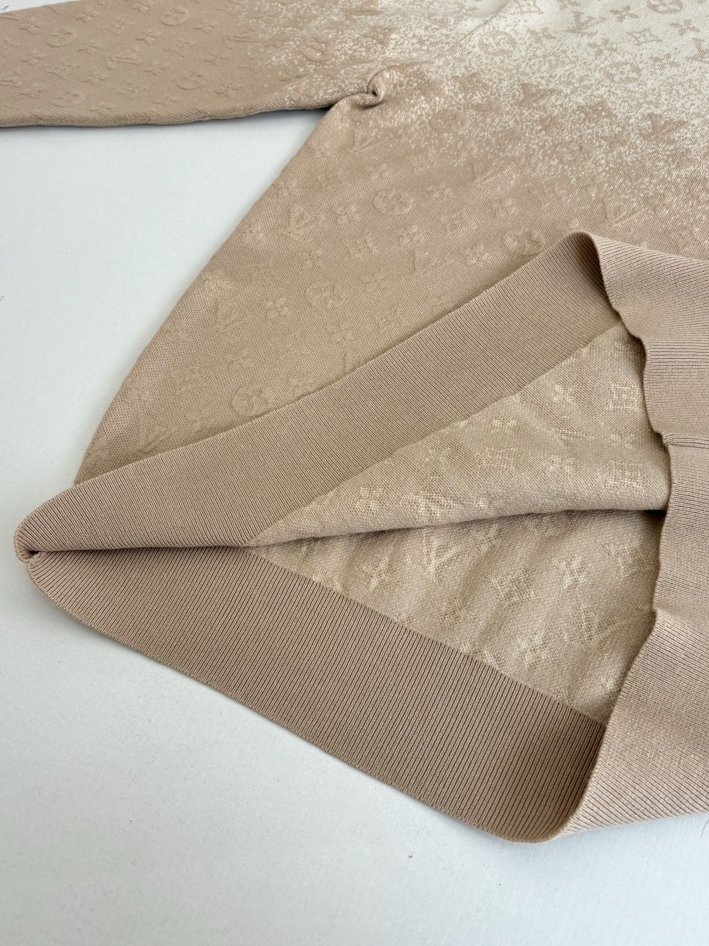 Folded light beige monogram sweater sleeve and ribbed hem