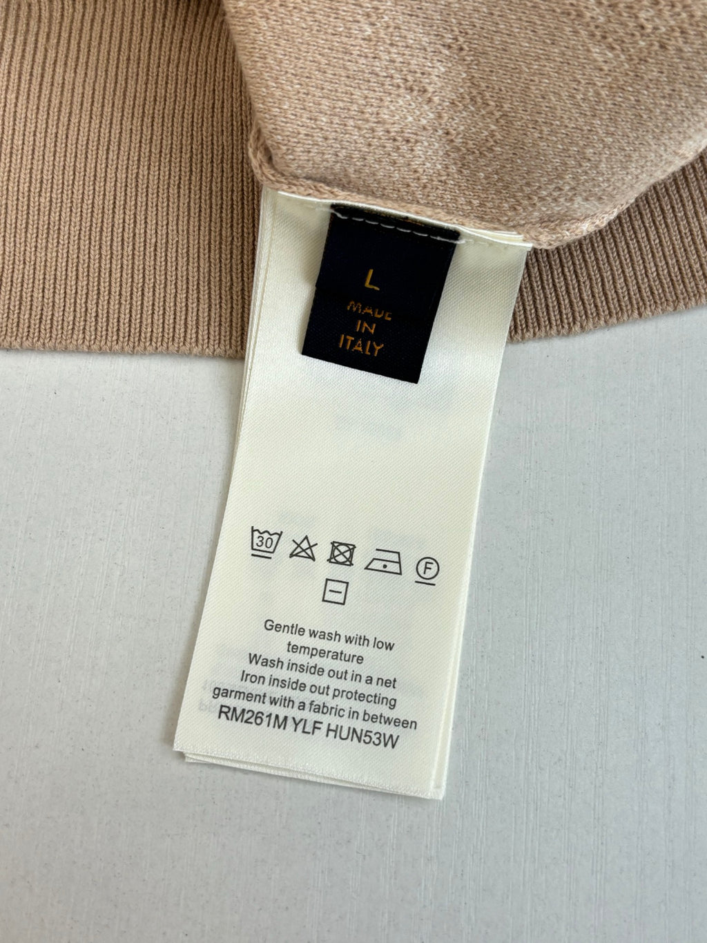Light beige sweater care label on inside hem