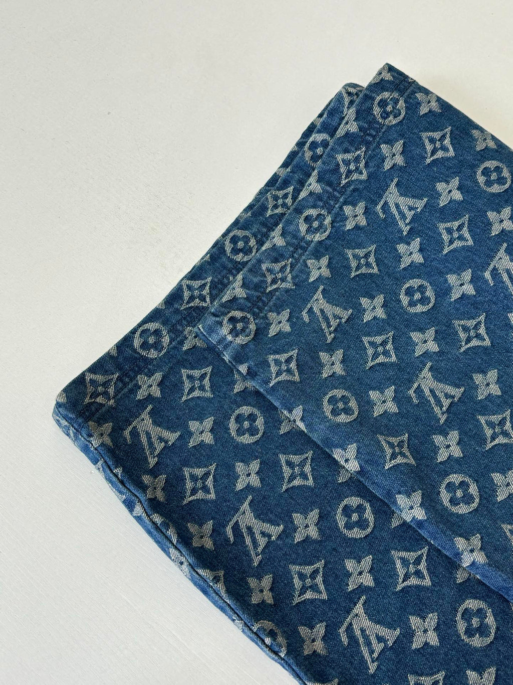 Louis Vuitton blue monogram denim shorts close-up, showing fabric texture and repeating pattern.