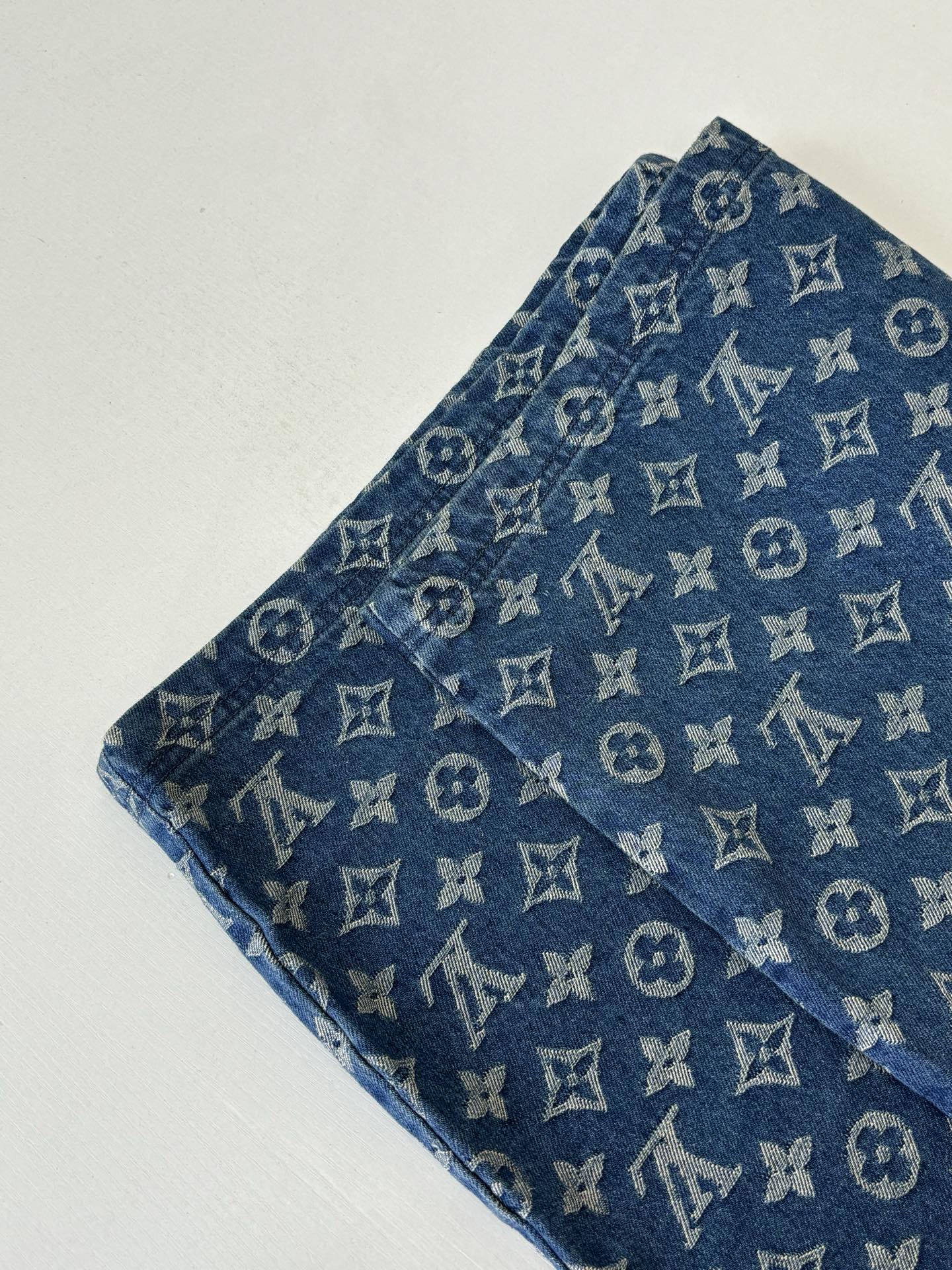 Louis Vuitton blue monogram denim shorts close-up, showing fabric texture and repeating pattern.
