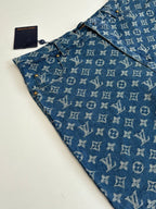 Louis Vuitton blue monogram denim shorts close-up, showing button and pocket stitching.