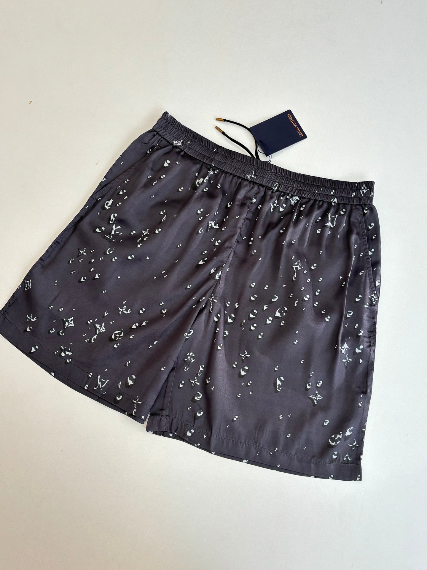 Dark navy printed shorts with elastic waistband, drawstring ties, and small white motifs