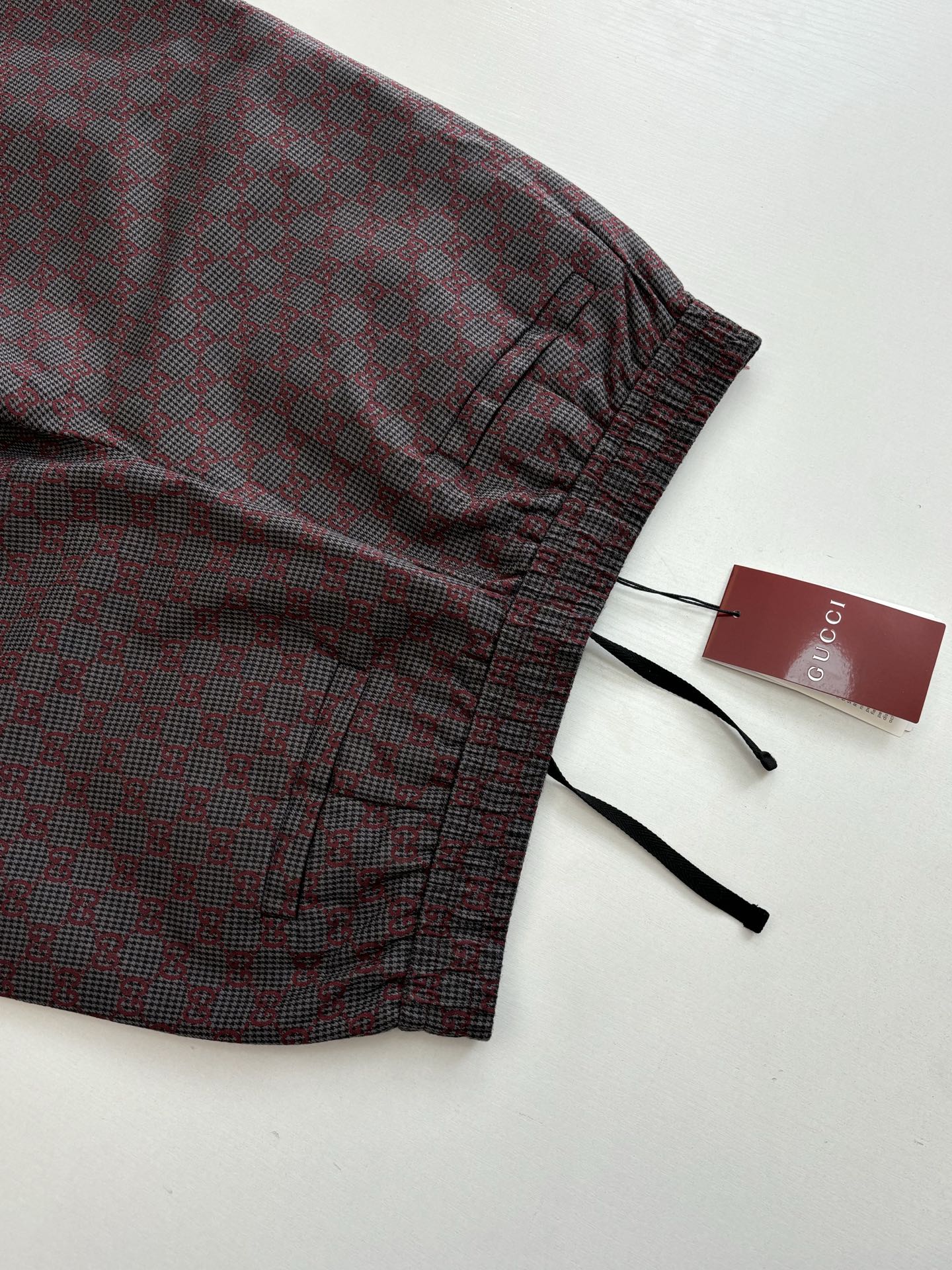 Gucci pants cuff detail with elastic hem and black drawstrings, folded