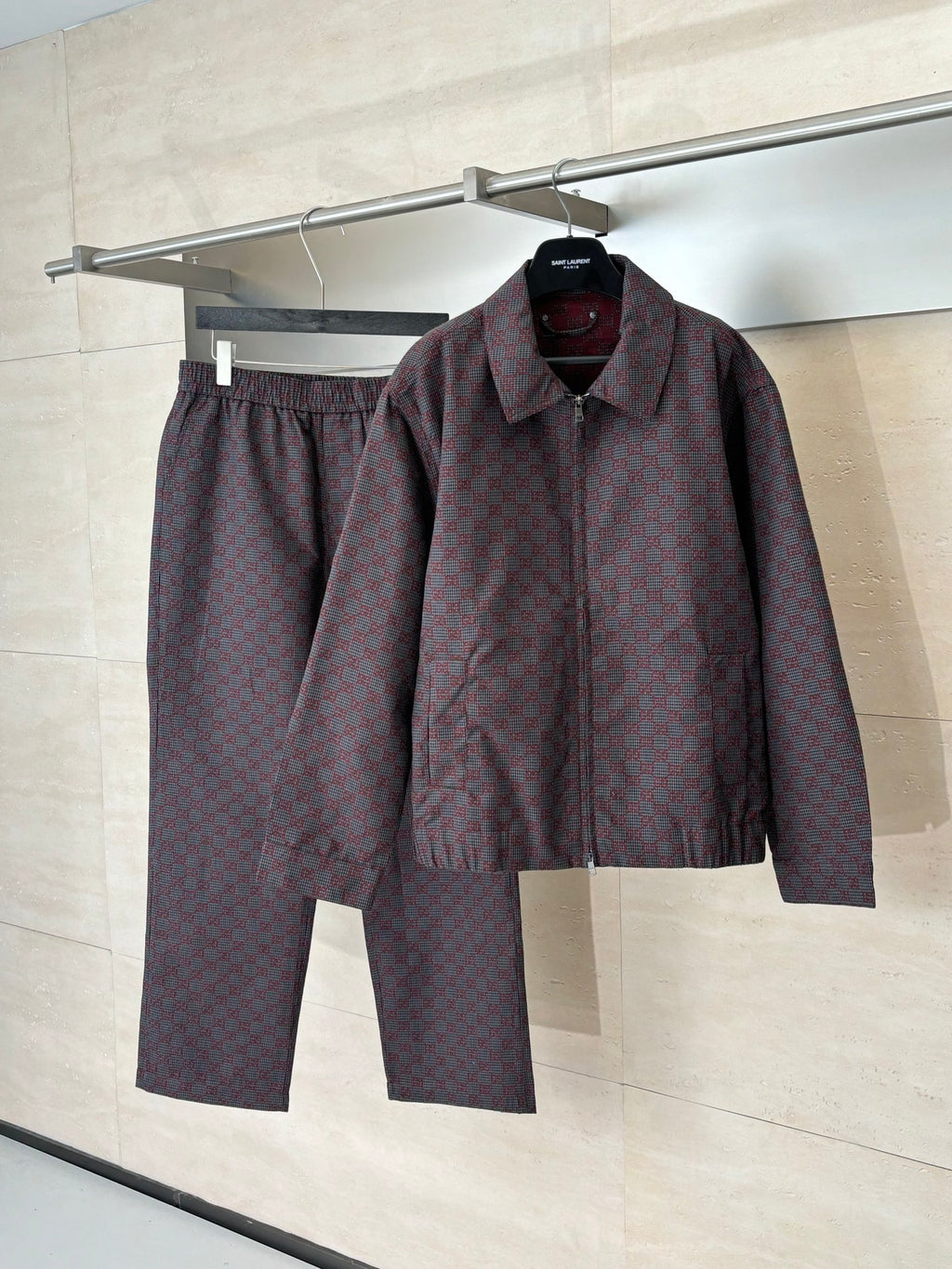 Gucci jacket and matching pants set on hangers, maroon and dark allover patterned fabric.