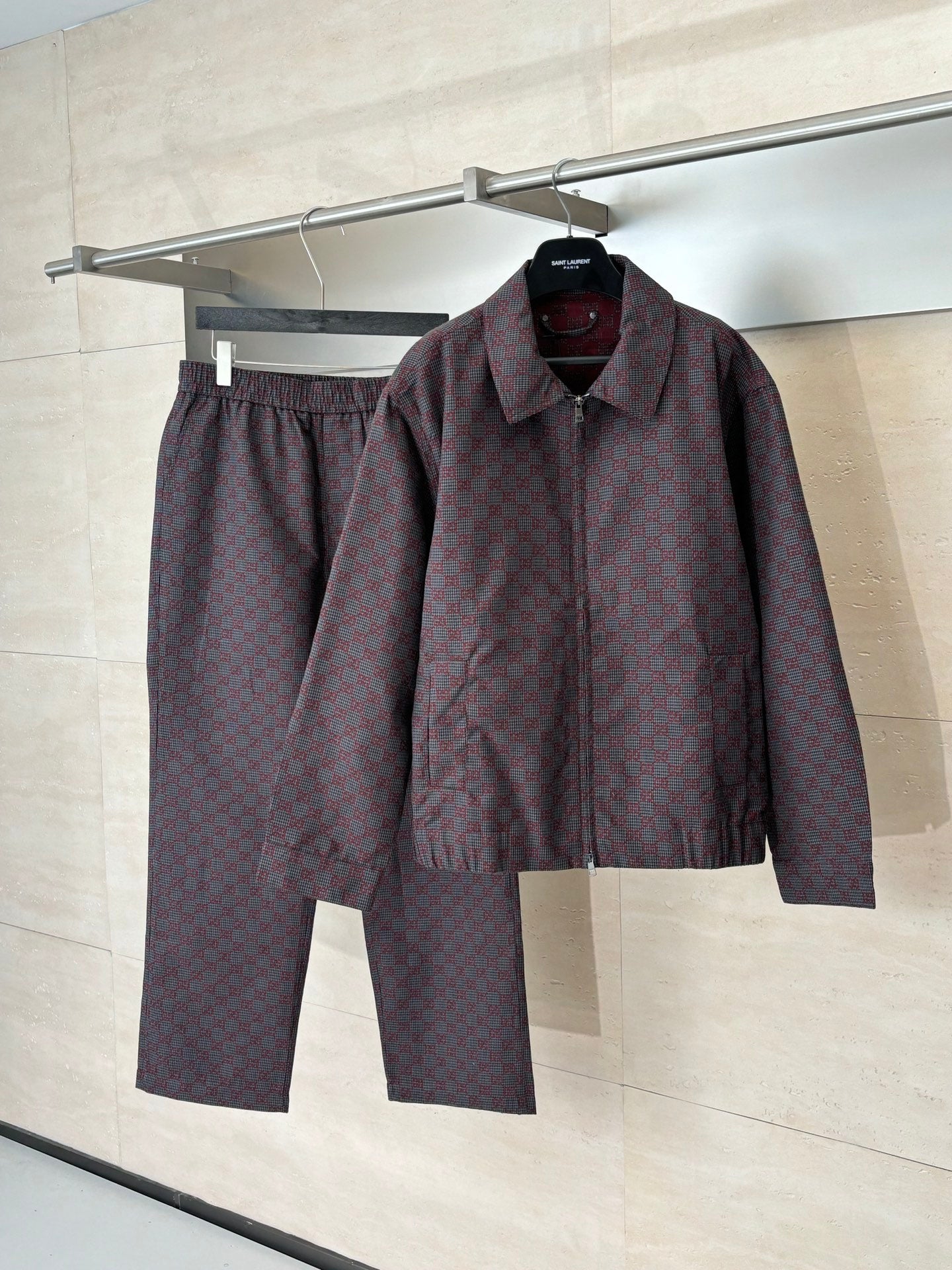 Gucci jacket and matching pants set on hangers, maroon and dark allover patterned fabric.